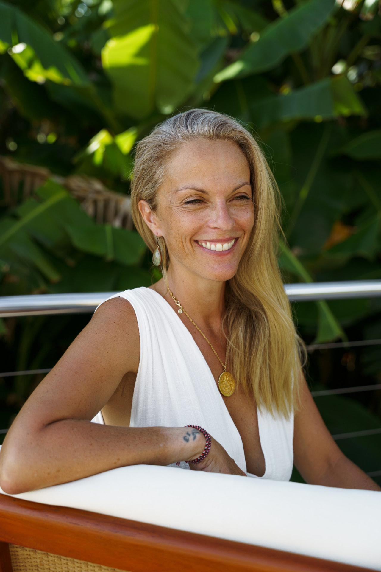 Marie Zollet souriante, en robe blanche, entourée de verdure